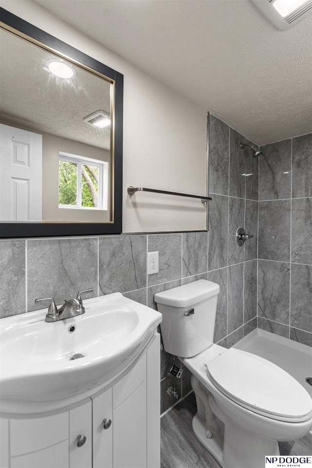 5437 S 18th St, Omaha, NE 68107 - full bathroom with tile walls, a shower stall, a textured ceiling, vanity, and toilet