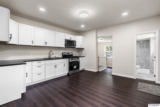 5437 S 18th St, Omaha, NE 68107 - kitchen featuring stainless steel appliances, a sink, dark countertops, white cabinets, and recessed lighting