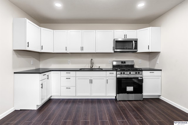 5437 S 18th St, Omaha, NE 68107 - kitchen with appliances with stainless steel finishes, a sink, baseboards, dark wood-style flooring, and dark countertops