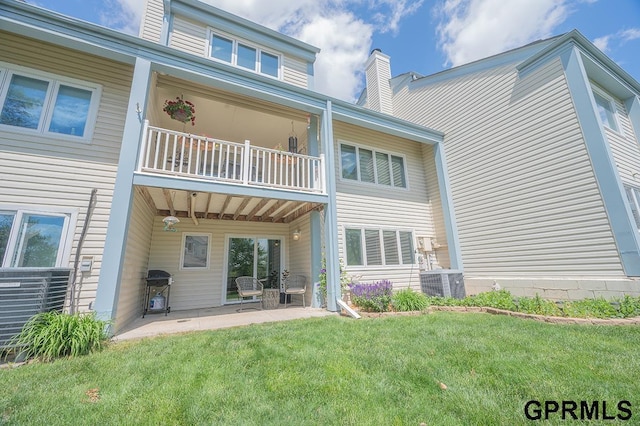 10755 Berry Plz, Omaha, NE 68127 - rear view of property featuring a balcony, a lawn, a patio area, cooling unit, and a chimney