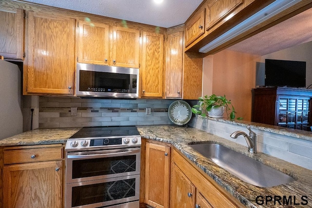 10755 Berry Plz, Omaha, NE 68127 - kitchen featuring appliances with stainless steel finishes, a sink, backsplash, light stone counters, and brown cabinets