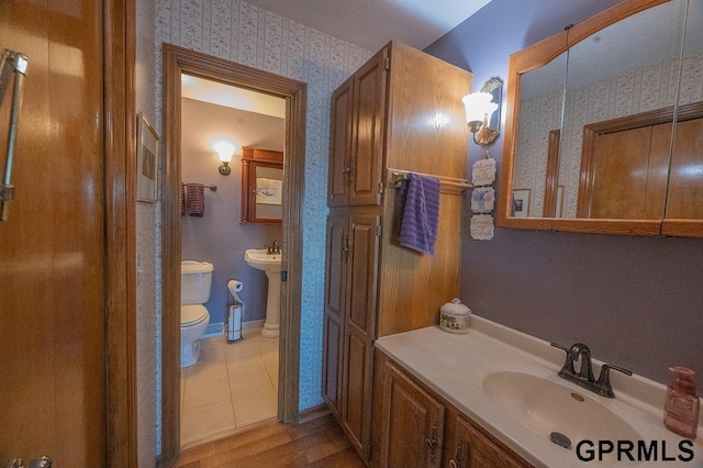 10755 Berry Plz, Omaha, NE 68127 - bathroom with a sink, wallpapered walls, toilet, and wood finished floors