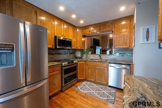 10755 Berry Plz, Omaha, NE 68127 - kitchen with appliances with stainless steel finishes, a sink, backsplash, light wood-style floors, and brown cabinetry