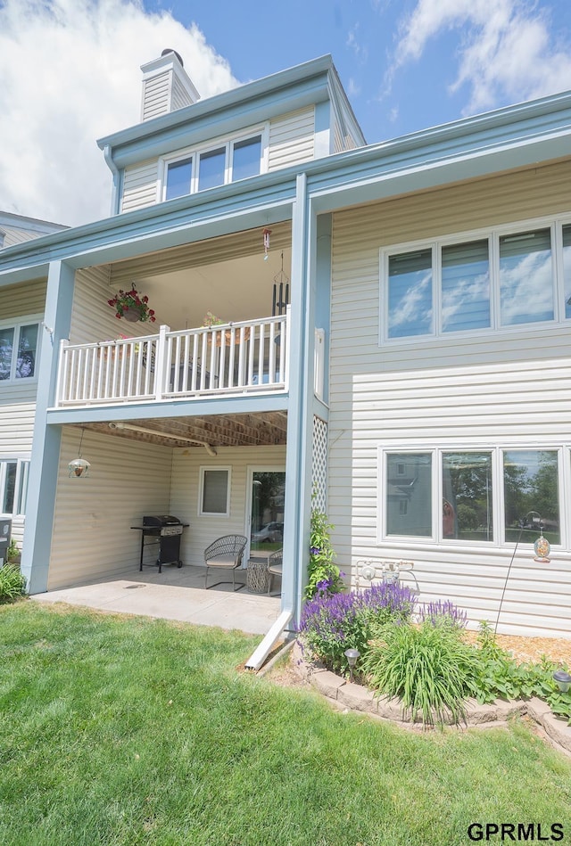10755 Berry Plz, Omaha, NE 68127 - rear view of property featuring a balcony, a chimney, a patio, and a lawn