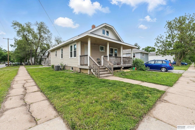 1152 N D St, Fremont, NE 68025 - view of front of house with covered porch, central air condition unit, a front yard, and a chimney