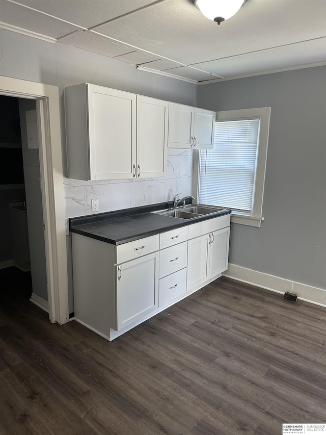 1152 N D St, Fremont, NE 68025 - kitchen with dark countertops, dark wood-style flooring, white cabinetry, tasteful backsplash, and a sink