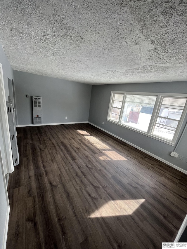 1152 N D St, Fremont, NE 68025 - unfurnished living room with a textured ceiling, dark wood-style floors, heating unit, and baseboards
