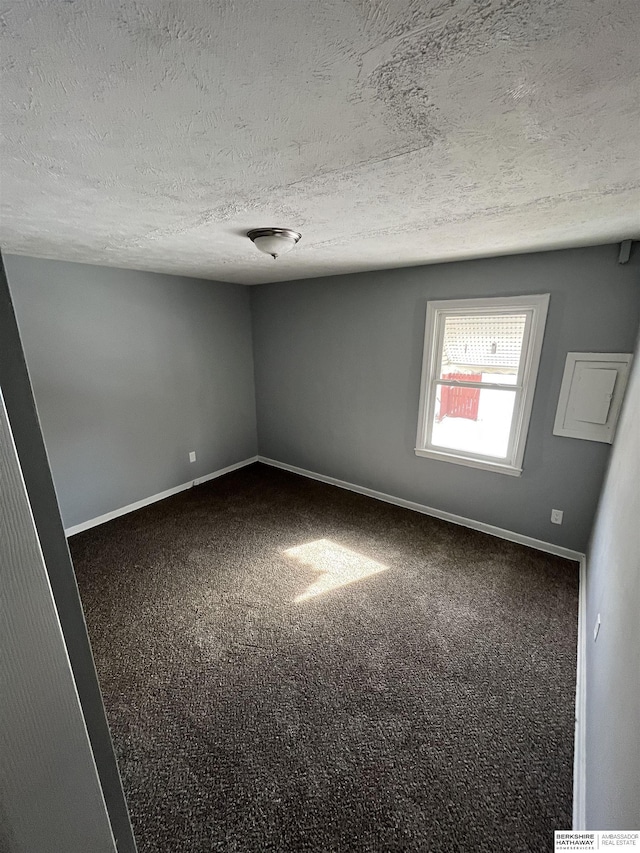 1152 N D St, Fremont, NE 68025 - empty room with dark carpet, baseboards, and a textured ceiling