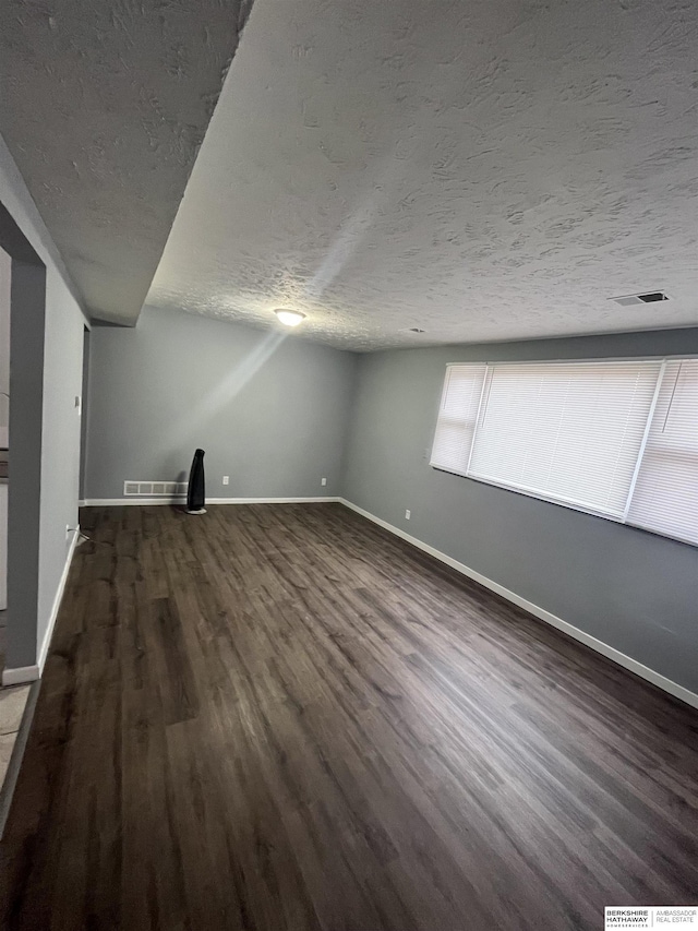 1152 N D St, Fremont, NE 68025 - unfurnished living room featuring baseboards, dark wood finished floors, and a textured ceiling