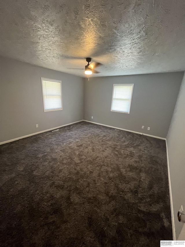 1152 N D St, Fremont, NE 68025 - unfurnished room featuring ceiling fan, dark colored carpet, a textured ceiling, and baseboards