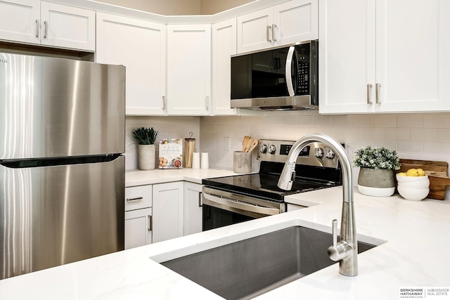 5445 S 51st St, Omaha, NE 68117 - kitchen featuring stainless steel appliances, white cabinetry, backsplash, and a sink