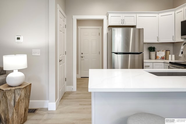 5445 S 51st St, Omaha, NE 68117 - kitchen with freestanding refrigerator, light wood-style floors, white cabinets, and baseboards