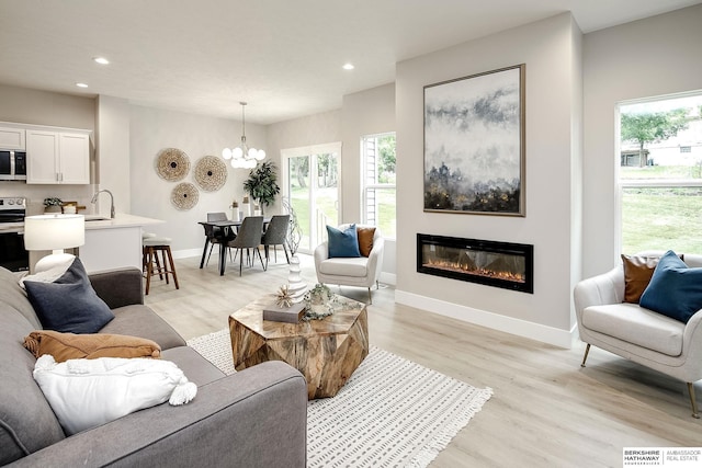 5445 S 51st St, Omaha, NE 68117 - living area featuring a chandelier, recessed lighting, light wood-style flooring, healthy amount of natural light, and a glass covered fireplace