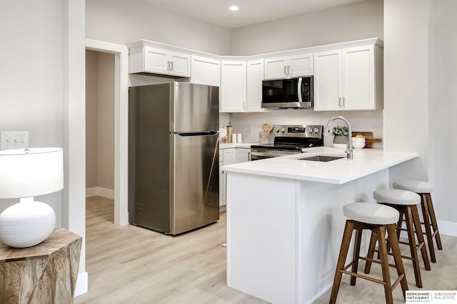 5445 S 51st St, Omaha, NE 68117 - kitchen featuring appliances with stainless steel finishes, a sink, a peninsula, white cabinetry, and light wood-style floors