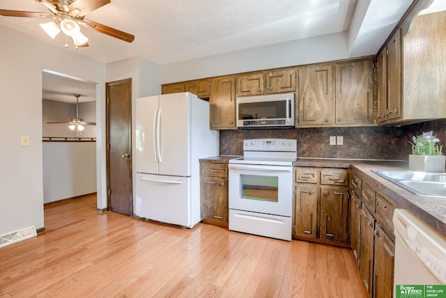 3209 Coffey Ave, Omaha, NE 68123 - kitchen with white appliances, a ceiling fan, backsplash, light wood-type flooring, and dark countertops