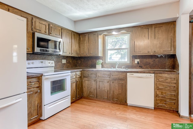 3209 Coffey Ave, Omaha, NE 68123 - kitchen featuring white appliances, a sink, decorative backsplash, a textured ceiling, and light wood-style floors