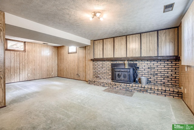 3209 Coffey Ave, Omaha, NE 68123 - unfurnished living room with a textured ceiling, wood walls, a wood stove, and light colored carpet