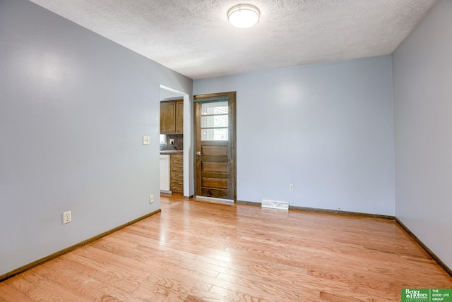 3209 Coffey Ave, Omaha, NE 68123 - empty room with a textured ceiling, light wood-type flooring, and baseboards