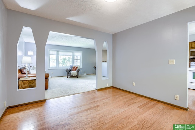 3209 Coffey Ave, Omaha, NE 68123 - unfurnished room with light wood-type flooring, baseboards, a textured ceiling, and arched walkways