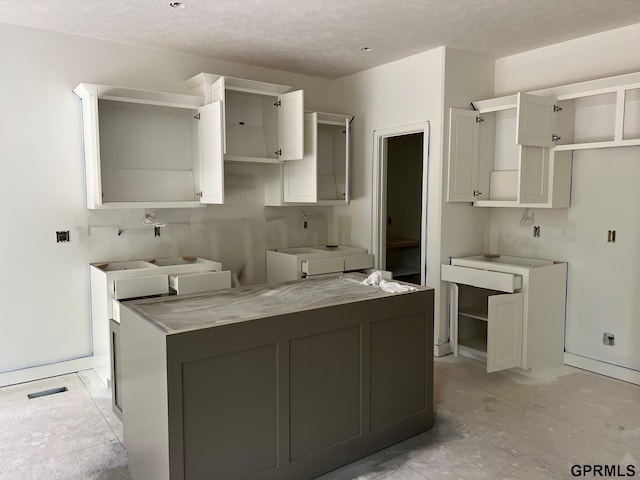 4510 Barksdale Dr, Bellevue, NE 68133 - kitchen with a textured ceiling, a kitchen island, white cabinets, and baseboards