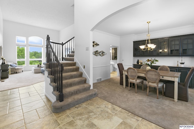 910 W Centennial Rd, Papillion, NE 68046 - dining space featuring light carpet, arched walkways, a chandelier, stone tile flooring, and ornamental molding