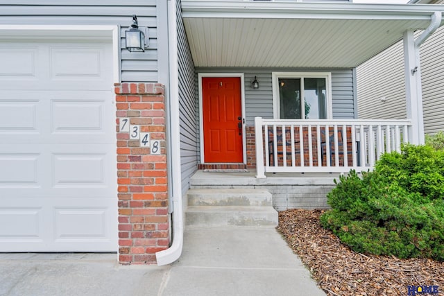 7348 N 19th St, Lincoln, NE 68521 - view of exterior entry with covered porch, brick siding, and a garage