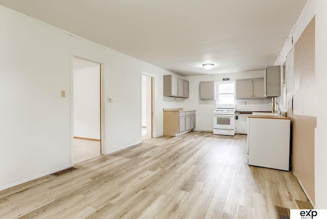 101 Station St, Shelby, IA 51570 - kitchen featuring white electric stove, gray cabinetry, light wood-type flooring, and a sink
