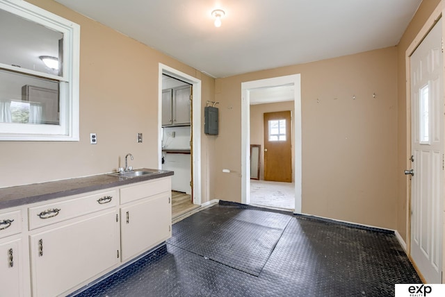 101 Station St, Shelby, IA 51570 - kitchen featuring a sink, white cabinets, dark floors, and baseboards
