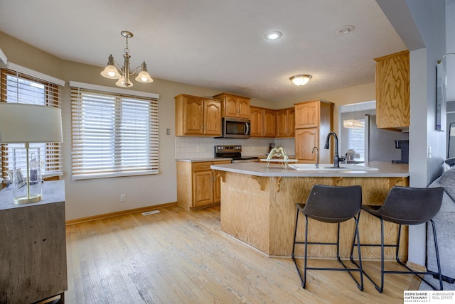 705 Ruby Rd, Papillion, NE 68133 - kitchen featuring stainless steel appliances, baseboards, a sink, a breakfast bar area, and light countertops