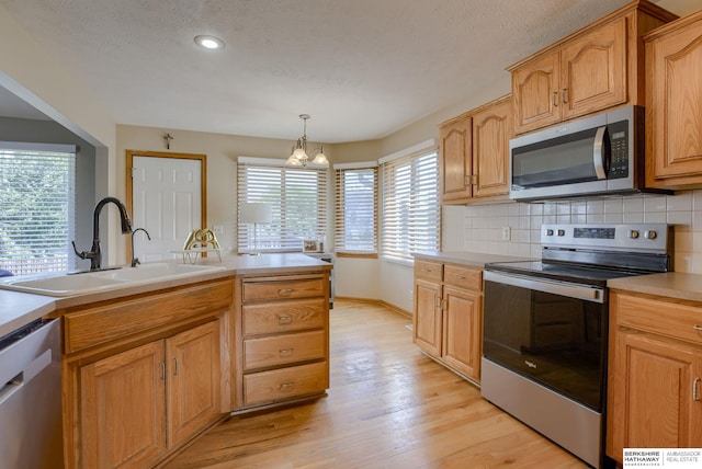 705 Ruby Rd, Papillion, NE 68133 - kitchen featuring stainless steel appliances, a sink, light wood-style floors, decorative backsplash, and light countertops