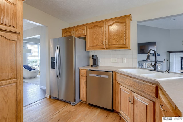 705 Ruby Rd, Papillion, NE 68133 - kitchen featuring stainless steel appliances, a sink, light wood finished floors, decorative backsplash, and light countertops