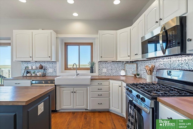 27896 Chestnut Rd, Treynor, IA 51575 - kitchen with appliances with stainless steel finishes, wood counters, a sink, white cabinets, and recessed lighting