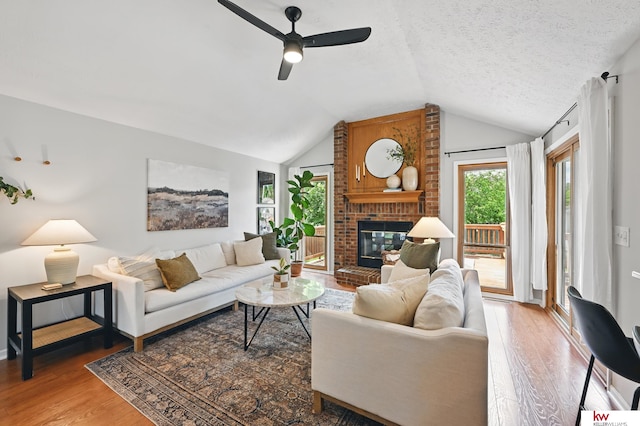 12231 Binney St, Omaha, NE 68164 - living room featuring wood finished floors, lofted ceiling, ceiling fan, a brick fireplace, and a textured ceiling