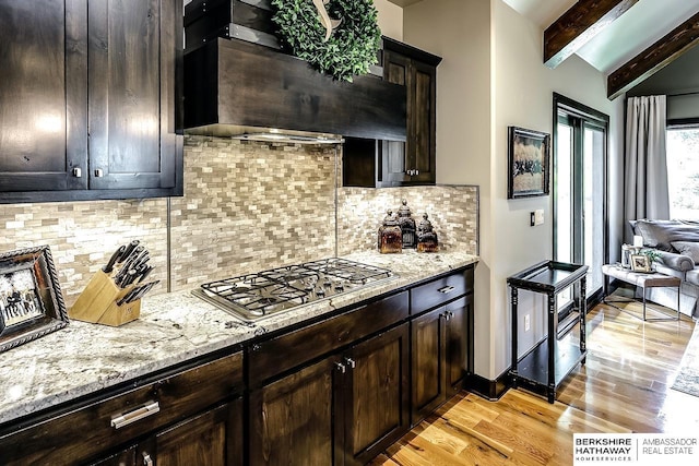 3334 S 188th Ave, Omaha, NE 68130 - kitchen featuring stainless steel gas stovetop, light wood-style flooring, custom exhaust hood, light stone counters, and dark brown cabinetry