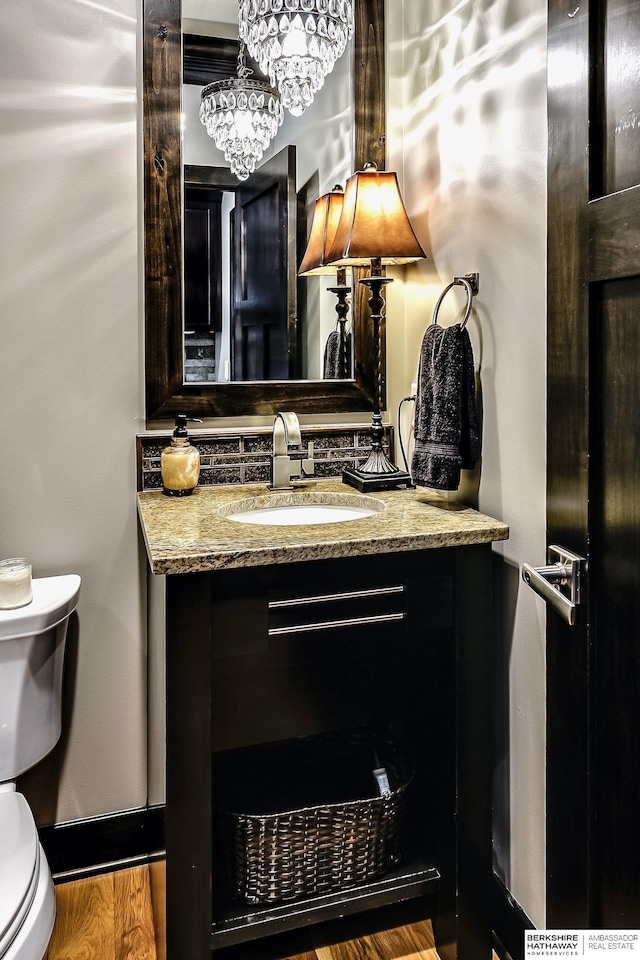 3334 S 188th Ave, Omaha, NE 68130 - half bathroom with toilet, vanity, backsplash, wood finished floors, and a chandelier