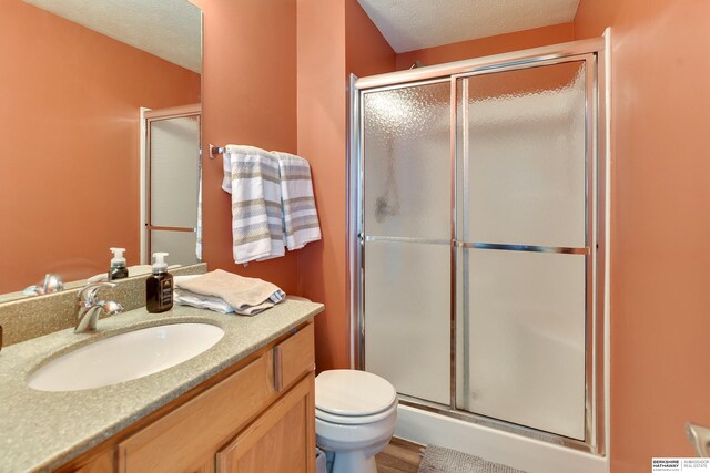 6704 N 149th Ave, Omaha, NE 68116 - full bath with a shower stall, vanity, toilet, a textured ceiling, and wood finished floors