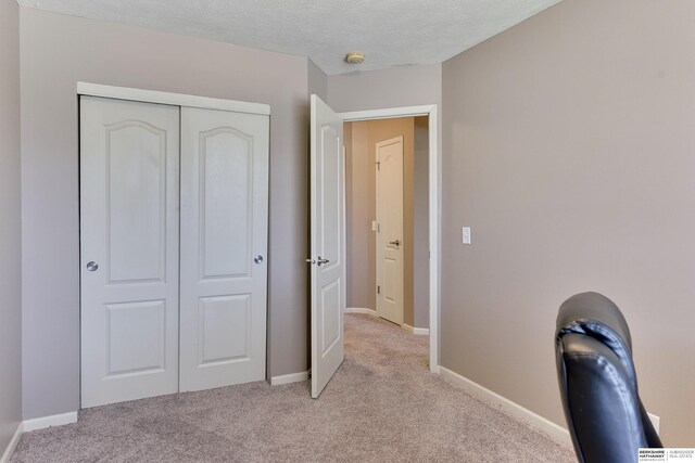 6704 N 149th Ave, Omaha, NE 68116 - unfurnished bedroom featuring light colored carpet, a closet, baseboards, and a textured ceiling