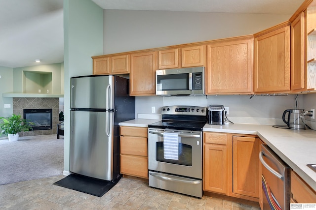 6704 N 149th Ave, Omaha, NE 68116 - kitchen with appliances with stainless steel finishes, vaulted ceiling, light countertops, a tiled fireplace, and open floor plan
