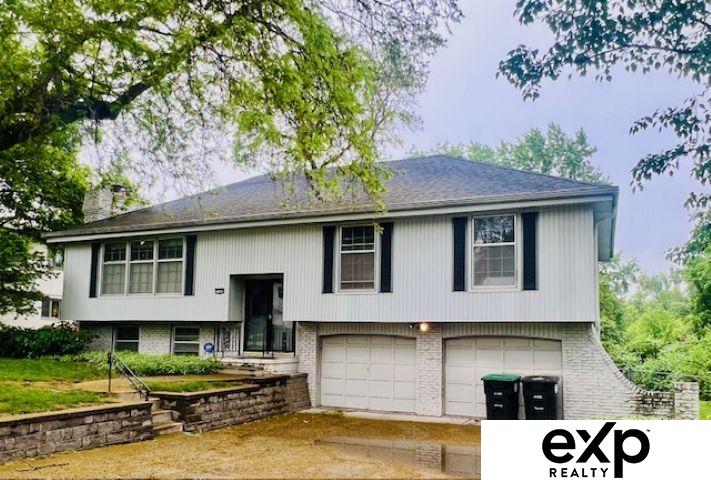 11665 Douglas St, Omaha, NE 68154 - raised ranch with an attached garage, concrete driveway, a chimney, and brick siding