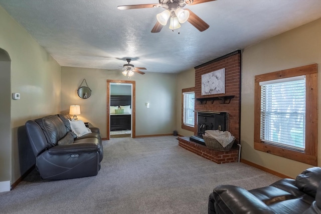 605 2nd St, Waterloo, NE 68069 - living room featuring ceiling fan, carpet, a brick fireplace, baseboards, and a textured ceiling