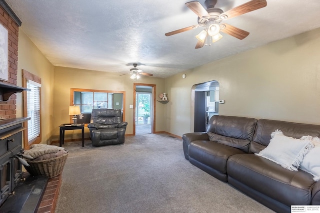 605 2nd St, Waterloo, NE 68069 - carpeted living room with a ceiling fan, arched walkways, a brick fireplace, baseboards, and a textured ceiling