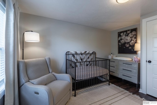 605 2nd St, Waterloo, NE 68069 - bedroom featuring dark wood finished floors and a nursery area