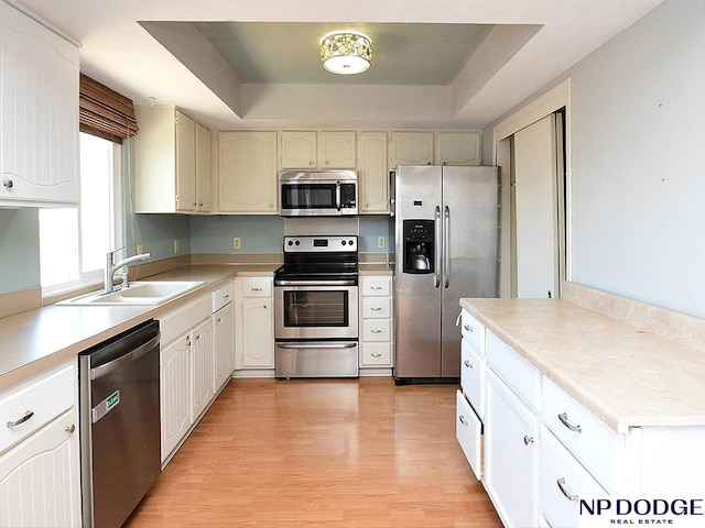 12067 Patrick Ave, Omaha, NE 68164 - kitchen with appliances with stainless steel finishes, a sink, light wood finished floors, and a tray ceiling