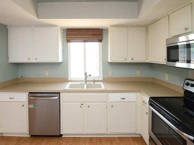 12067 Patrick Ave, Omaha, NE 68164 - kitchen with appliances with stainless steel finishes, a sink, light wood finished floors, light countertops, and white cabinets