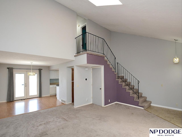 12067 Patrick Ave, Omaha, NE 68164 - unfurnished living room featuring a towering ceiling, stairs, baseboards, and light colored carpet