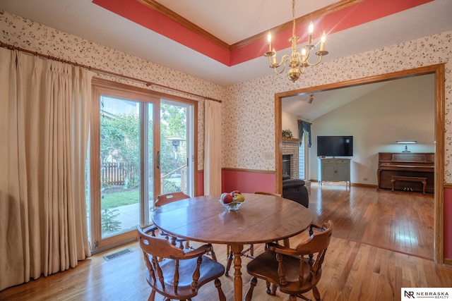 9910 Ohio St, Omaha, NE 68134 - dining space with a chandelier, a fireplace, light wood finished floors, wallpapered walls, and vaulted ceiling