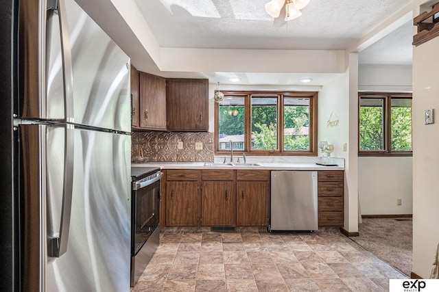 1214 Happy Hallow Ct, Plattsmouth, NE 68048 - kitchen with stainless steel appliances, light countertops, a sink, backsplash, and brown cabinetry