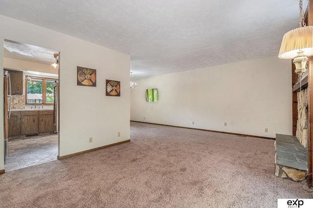 1214 Happy Hallow Ct, Plattsmouth, NE 68048 - unfurnished living room featuring light colored carpet, a chandelier, a sink, baseboards, and a textured ceiling