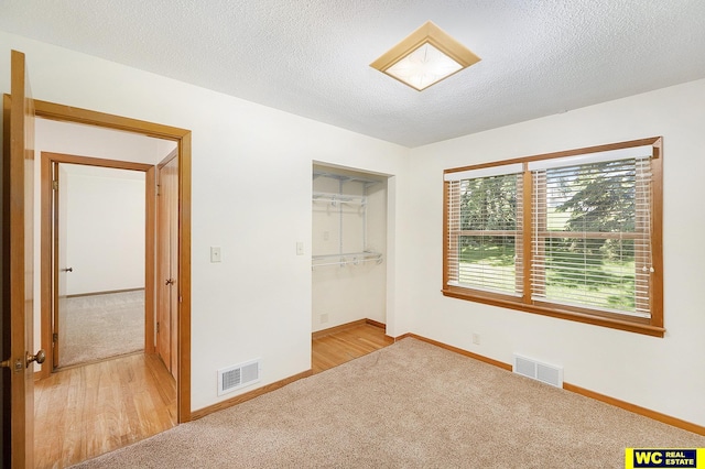 1341 Wilbur St, Blair, NE 68008 - unfurnished bedroom featuring light carpet, baseboards, a textured ceiling, and light wood-style floors