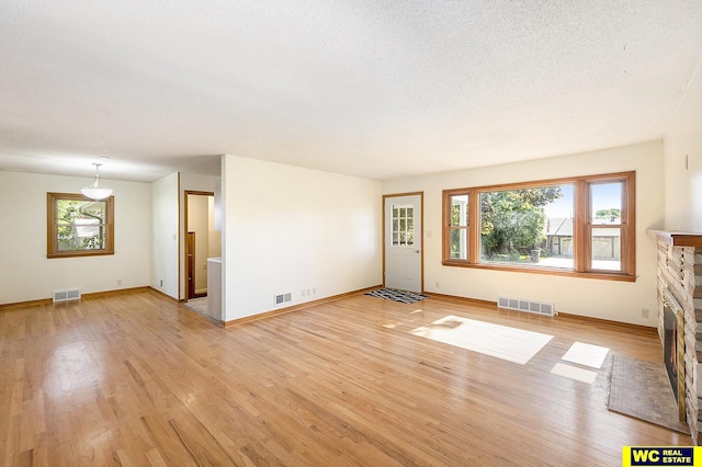 1341 Wilbur St, Blair, NE 68008 - unfurnished living room featuring light wood-type flooring, healthy amount of natural light, and a stone fireplace